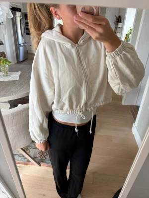 Offwhite croppad hoodie med dragkedja - Säljer en croppad hoodie med dragkedja framtill och huva. Något nopprig. 