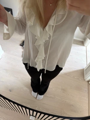 Vit blus med volang och knytband - Säljer en vit blus med långa ärmar, volangdetaljer. Knappt använd från Zara.  
