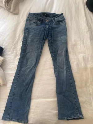 Blå bootcut jeans från Ltb - Säljer ett par ljusblå bootcut jeans från Ltb med klassisk femficksmodell och snygga slitningar. Jeansen har normal midja och är tillverkade i mjukt denimtyg som sitter skönt. Perfekta för en avslappnad och trendig look. Storlek 26/32 modell valerie, sitter som xs/s
