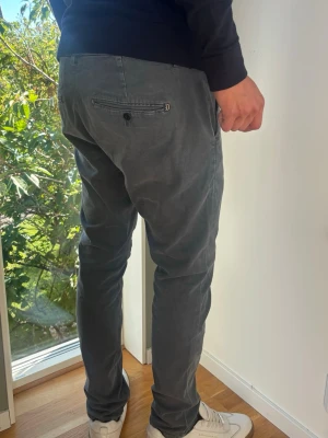 Dondup Chinos Herr Grå Storlek 35 Made in Italy  - Exklusiva italienska chinos från Dondup i en sofistikerad tvättad mörkgrå nyans. Elegant modell i storlek 35. Premiumdetaljer som mönstrad linning och metall-D på bakfickan (88% bomull, 10% polyester, 2% elastan). Skick: Grade A/B. Använda väldigt lite! Mått [platt]: (Jämför med en byxa som du gillar) A: Midja: 45 cm B: Längd: 104 cm C: Benslut: 17 cm D: Lår: 28 cm Passar okej på mig på bilden som är 189 cm lång (dubbelkolla mått) Tveka inte att höra av dig vid frågor. Skickas fort!