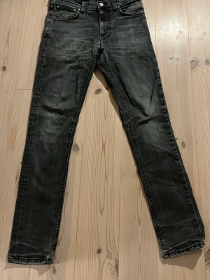 Svarta Nudie Jeans - Säljer ett par Nudies med en snygg tvätt. Jeansen har klassisk femficksmodell, knappgylf och raka ben. Materialet är denim med lite stretch för skön passform. Perfekta till en avslappnad streetstil.