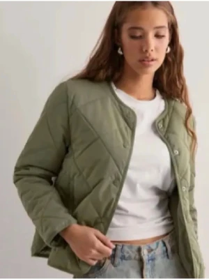 Olivgrön quiltad pufferjacka - Snygg olivgrön pufferjacka med quiltat mönster och rundad krage. Jackan har tryckknappar framtill och raka ärmar. Perfekt för kalla dagar och ger en trendig look till din outfit.knappt använd! Nypris 700kr