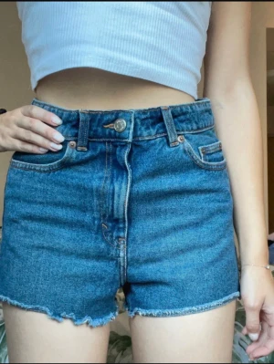 Blå jeansshorts från Monki - Jeansshorts i storlek 25 från monki. De är som en liten xs, så skulle rekommendera till de som brukar ha storlek xs. Sitter ändå bra på mig som brukar ha xs-s och är 173 cm, slutar precis under rumpan så de är i det kortare laget. Väldigt fint skick!!