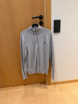 Ljusgrå ziptröja från Ralph Lauren - Ljusgrå ziptröja från Ralph Lauren. Skick 9/10. Helt utan defekter då den är använd max 3 gånger.
