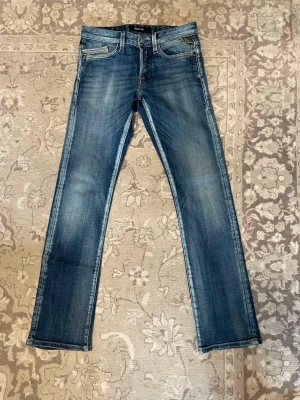 Replay jeans - SÄLLSYNYA! Säljer ett par blå jeans med raka ben och utvättad design. Jeansen har klassisk femficksdesign, normal midja och dragkedjegylf. Passformen är avslappnad men ändå snyggt åtsittande över låren.