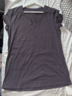 Mörkgrå v-ringad t-shirt Basic You - En enkel och stilren mörkgrå t-shirt från Basic You i ekologisk bomull. T-shirten har v-ringning och korta ärmar, perfekt för en avslappnad look. Passformen är normal och materialet känns mjukt mot huden.