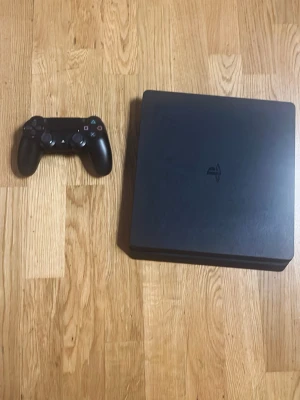 PlayStation 4 Slim med handkontroll - Säljer en svart PlayStation 4 Slim med tillhörande svart DualShock 4-handkontroll. Konsolen har en stilren, matt finish och den klassiska PlayStation-loggan på ovansidan. Perfekt för gaming och streaming hemma. Har bara använt 1 gång så nästan helt ny passa på och köp! 