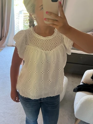 Vit broderad blus med volangärm - Söt vit blus i broderad bomull med hålmönster och volangärmar.  Perfekt till jeans eller kjol för en fräsch och somrig look. Är från missäy för 299kr men kan sälja runt 80kr, knappt använd 