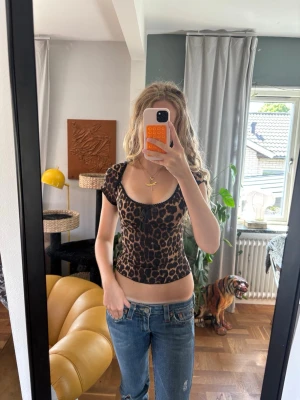 Leopardmönstrad croppad topp - Säljer en croppad topp med leopardmönster och korta ärmar. Toppen har en söt liten rosett framtill och svarta spetsdetaljer vid halsringningen. Materialet känns stretchigt och lätt, perfekt för en trendig look. Är omsydd lite slarvigt för att sitta tightare men det syns inte på utsidan, lappen är bortklippt men tröjan är ifrån SHEIN.