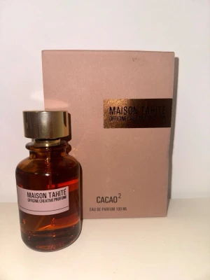 Maison Tahité Cacao² Eau de Parfum 100ml - Maison Tahité Cacao² Eau de Parfum kommer i en elegant brun glasflaska med guldfärgad kork och matchande ask. Doften är inspirerad av kakao och flaskan rymmer 100 ml. Perfekt för dig som gillar unika och lyxiga parfymer. Endast testsprutad !!