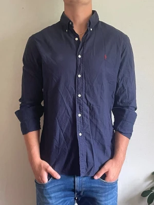 Ralph lauren skjorta - Säljer denna riktigt snygga mörkblåa Ralph lauren skjorta! Helt felfri och mycket bra skick! Storlek L modell slim fit, den är 76 cm lång och 51 cm bred, hör av dig vid frågor!