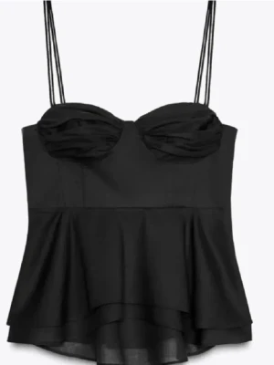 Svart peplum topp med tunna band - Säljer en svart peplum topp med tunna axelband och draperad byst. Toppen har en volang nedtill.