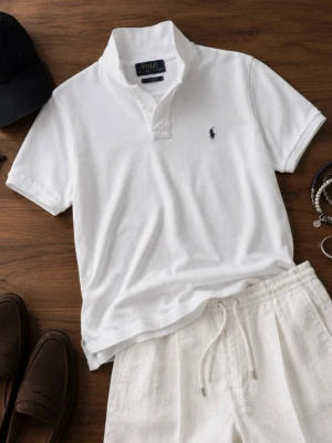 Vit pikétröja från Polo Ralph Lauren - Klassisk vit pikétröja från Polo Ralph Lauren med korta ärmar och krage. Tröjan har den ikoniska broderade loggan på bröstet och knäppning vid halsen. Tillverkad i bomull för en skön och luftig känsla. Perfekt till sommaren! Storlek S.