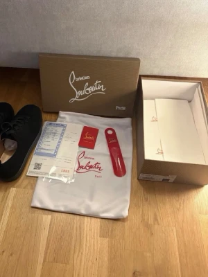  Christian Louboutin svarta - Stilrena svarta sneakers från Christian Louboutin med klassisk låg profil och svarta skosnören. Skorna har en diskret design och kommer med originalkartong, dustbag och tillbehör. Perfekta för dig som vill ha en exklusiv touch på din outfit. Passar 42/43/41