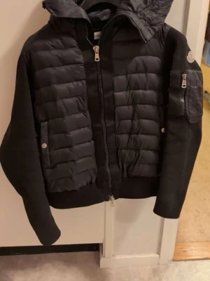 Moncler Cardigan, svart - Snygg svart cardigan i storlek M men sitter som S. Riktigt snygg och varm jacka passar till alla tillfällen. I fint skick finns endast små skavanker se på bilderna”. Mycket bra kvalitet, bara att höra av sig vid frågor!