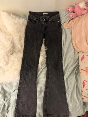 Svarta bootcut jeans med hög midja - Säljer ett par svarta bootcut jeans med hög midja och klassisk femficksdesign. Jeansen har en lätt tvättad look och vida ben från knät och ner. Perfekta för dig som gillar retrostil och vill ha ett par bekväma jeans med snygg passform.