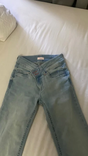 Ljusblå bootcut jeans med mid waist - Säljer ett par ljusblå jeans med bootcut-modell och mid waist. Jeansen har klassiska fem fickor och dragkedja med knappstängning. Materialet är mjukt denim som ger en skön passform och en avslappnad look. Aldrig använd då dom är för stora. Från NELLY