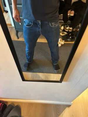 Blå Replay jeans  - Säljer ett par blå jeans med straight fit. Jeansen har klassiska fem fickor, kontrastsömmar och en läderpatch bak i midjan. Materialet är denim i bomull och passformen är avslappnad och trendig. Längden är (32)