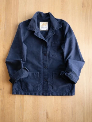 Le Mont St Michel Navy Chore Jacket, size S - Stilren mörkblå overshirt i bomull med tre praktiska fickor framtill och klassisk krage från kända franska Le Mont Saint Michel. Jackan har knäppning med tre knappar och uppvikta ärmslut. Perfekt för lager-på-lager och enkel att matcha med olika outfits. Size 40/S. 