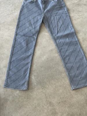 Grå raka jeans med fem fickor - Säljer ett par gråa axel arigato jeans med rak passform och klassisk femficksdesign. Jeansen har normal midja och är tillverkade i ett mjukt denimtyg. Perfekta för en avslappnad och stilren look.