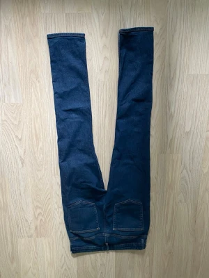 Mörkblå skinny jeans - Säljer ett par mörkblå skinny jeans med klassisk femficksdesign och smal passform. Jeansen har två bakfickor och är tillverkade i stretchigt denimtyg för en bekväm känsla. Perfekta att matcha med sneakers eller boots.