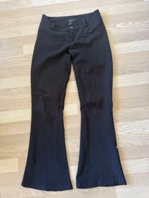 Svarta kostymbyxor - Snygga svarta kostymbyxor med bootcut passform och dubbla knappar fram. 