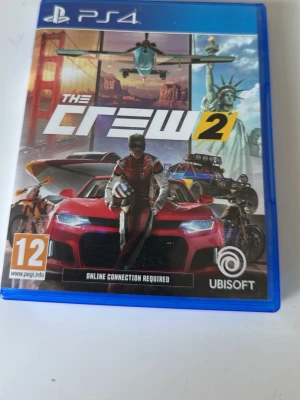 The Crew 2 till PS4 - The Crew 2 till PlayStation 4 är ett racingspel där du kan köra bilar, motorcyklar, båtar och flygplan över hela USA. Omslaget är blått med färgstarka fordon och frihetsgudinnan i bakgrunden. Spelet kräver internetuppkoppling och har PEGI 12.