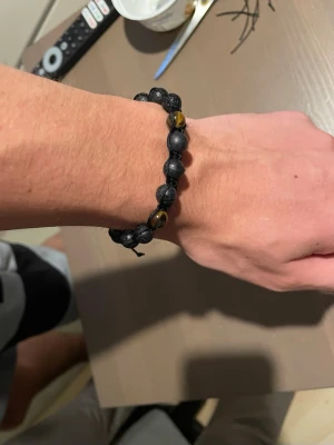 Armband kille - Jättesnyggt armband för män, har gjort det själv och kan göra med svarta,bruna,mörkgröna pärlor om så önskas. Den på bilden har svarta pärlor med några bruna. Den är slitstark och storleken är justerbar. Den är enkel att ta på och av. 