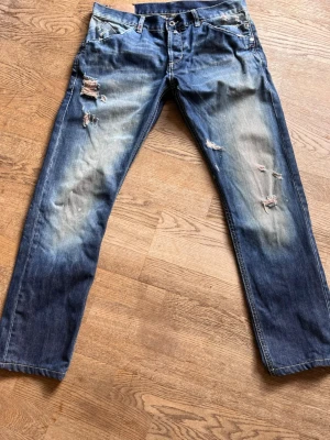 Dondup Jeans - Säljer ett par dondup jeans med raka ben och slitningar på både lår och knän. Jeansen är normal/ varken baggy eller skinny men passar dig perfekt om du ska ha en mer avslappnad (laidback) utseende. Skriv om du vill diskutera pris! Sitter som en 29a runt midjan