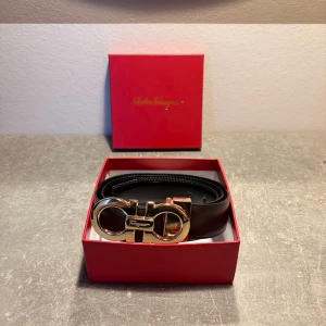 Ferragamo bälte - Ferragamo-bälte i riktigt fint skick. Reversible modell med svart på ena sidan och brunt på den andra, så du kan matcha det med i princip allt. Guldfärgat Gancini-spänne som ger en clean och stilren look.
