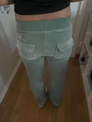 Gröna juicybyxor - Passar även S och M.Snygga ljusgröna mjukisbyxor i mjukt velourmaterial. Byxorna har bred resår i midjan med dragsko och två fickor med lock och knappar bak. Perfekta för en chill och avslappnad stil.