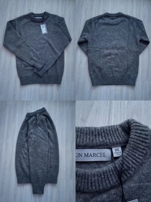 Grå stickad tröja från Jon Marcel - Mysig grå stickad tröja från Jon Marcel med rund halsringning och ribbstickade muddar vid ärmslut och nederkant. Enkel och stilren design som passar perfekt till många olika outfits.