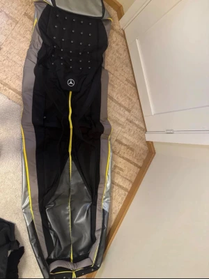 Mercedes svart/grå golfbag - Säljer en svart och grå golfbag med gula detaljer och Mercedes-logga. Klädseln har flera små hål för ventilation och är tillverkad i slitstarkt material, perfekt för en sportig look.