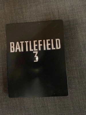 Battlefield 3 Steelbook PS3 - Battlefield 3 i exklusivt svart steelbook-fodral till PlayStation 3. Innehåller spel, omslag och bonusmaterial. Perfekt för dig som gillar actionfyllda shooters och samlarutgåvor. Snygg design med tydlig logga på framsidan.
