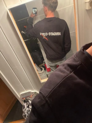 Axelarigato sweatshirt  - Svart sweatshirt med vitt tryck 'ARIGATO @2014' på bröstet och ryggen. Tröjan har rund halsringning, långa ärmar och ribbade muddar vid ärmslut och nederkant. Perfekt för en avslappnad och stilren look.