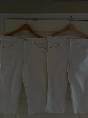 Vita raka jeans med fem fickor - Säljer två par vita jeans med klassisk femficksdesign och raka ben. Jeansen har knappgylf och detaljer i kopparfärg. Perfekta för en fräsch och stilren look. Materialet är denim i bomull/ elastisk. Jag har två storlekar 38 och 40. 