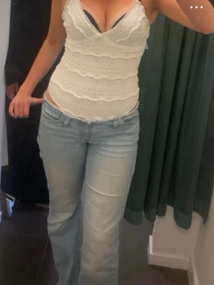 Vit body med spets - Säljer en söt vit body med spetsdetaljer och smala axelband. Toppen är figurnära och har v-ringning samt fina spetslager över hela plagget. Perfekt att styla med jeans eller kjol för en trendig look. Aldrig använd. Passar storlek S/m 