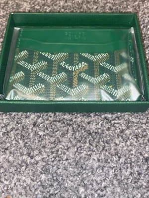 Grön korthållare  - Snygg grön korthållare med det klassiska mönstret i vitt Tillverkad i canvas med läderdetaljer och har plats för flera kort. Kommer i originalförpackning och har en stilren, exklusiv look.