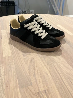 Maison margiella - Maison Margiella. Ovandelen är i en mix av mocka och slätt läder, och insidan är ljusbeige. Klassisk låg modell som passar till det mesta och ger en clean look. Använda mycket få tal gånger, så är k mycket bra skick