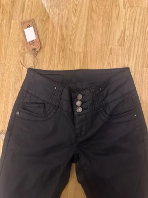 bootcut vaxade jeans - Snygga svarta vaxade bootcut jeans med låg midja och tre knappar framtill❤️aldrig använts! Säljer pga för små. 