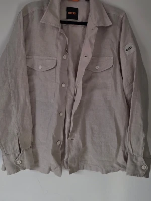 Beige linneskjorta från BOSS - Skit snygg Hugo Boss beige linneskjorta, storlek S men passar även M, oanvänd. Endast provad hemma. Den kan även användas som en overshirt 👌🏼