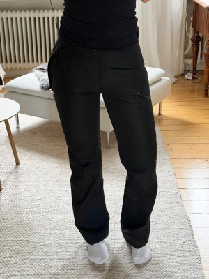 Praktiska & snygga regnbyxor från Neomondo - Superfina och funktionella svarta regnbyxor i storlek S. Smarta fickor med dragkedja och justerbara benslut så de sitter perfekt över skorna. 