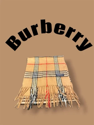 Burberry halsduk - Klassisk beige halsduk från Burberry med ikoniskt rutmönster i svart, vitt och rött. Halsduken har fransar i båda ändar och är tillverkad i mjukt material som känns lyxigt och stilrent. Perfekt accessoar för att lyfta din outfit. Halsduken är aldrig använd och nypris ligger runt 5000.            Skriv vid frågor, pris kan diskuteras 🤝