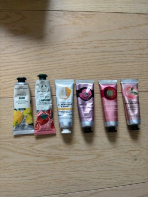Handkrämer från The Body Shop 6-pack - Säljer ett set med sex handkrämer från The Body Shop i dofterna mango, jordgubb, almond milk & honey, british rose, strawberry och pink grapefruit. Tubarna är i metall och rymmer 30 ml vardera. Tyvärr är vissa öppnade och använda lite utav, men nästan alla är helt fulla. Perfekt för dig som vill ha återfuktande handkräm med fräscha dofter.