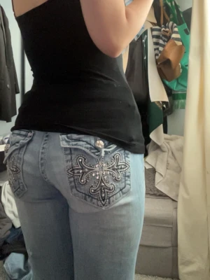 Ljusblåa low waist bootcut miss me jeans  - Säljer ett par ljusblå jeans med snygga broderier och nitar på bakfickorna. Jeansen har raka ben och detaljerade sömmar, samt en metallplatta vid linningen bak. Perfekta för dig som gillar statement-plagg och coola detaljer. Pris kan såklart diskuteras 