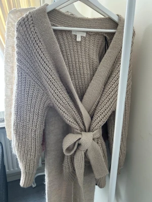 Stickad kofta med skärp H&M - Säljer denna stickade beige/bruna koftan från H&M.