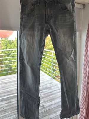 Levis jeans raka med slitningar - Säljer ett par grå jeans med raka ben och snygga slitningar framtill. Jeansen har klassisk femficksmodell och en diskret tvättad look. Passar perfekt till en avslappnad stil och är tillverkade i mjukt denimtyg.