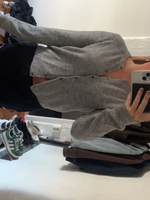 Grå kofta från H&M, M - Mysig grå kofta från H&M i storlek M. Koftan har rund halsringning, långa ärmar och knäppning framtill med små knappar. Tillverkad i mjukt stickat material som passar perfekt till lager på lager och chill vardagsstil.