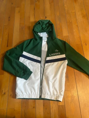 Lacoste Vindjacka - Den är nästan ny, använt ett fåtal gånger men den är i nyskick! Storlek S. Inte jättebra bilder men om du vill ha mer bilder så är det bara att skicka ett DM! Och vid andra frågor! 