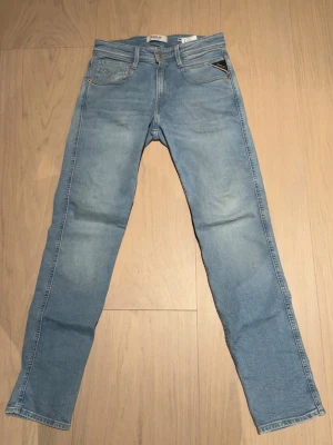Ljusblå raka jeans från Replay - Säljer ett par ljusblå jeans från Replay med klassisk femficksdesign och raka ben. Jeansen har en snygg tvättad look och är tillverkade i mjukt denimtyg. 
